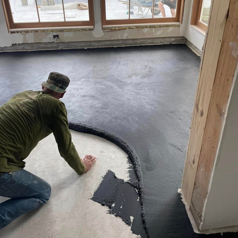 Bare concrete floor being troweled with a dark gray coating