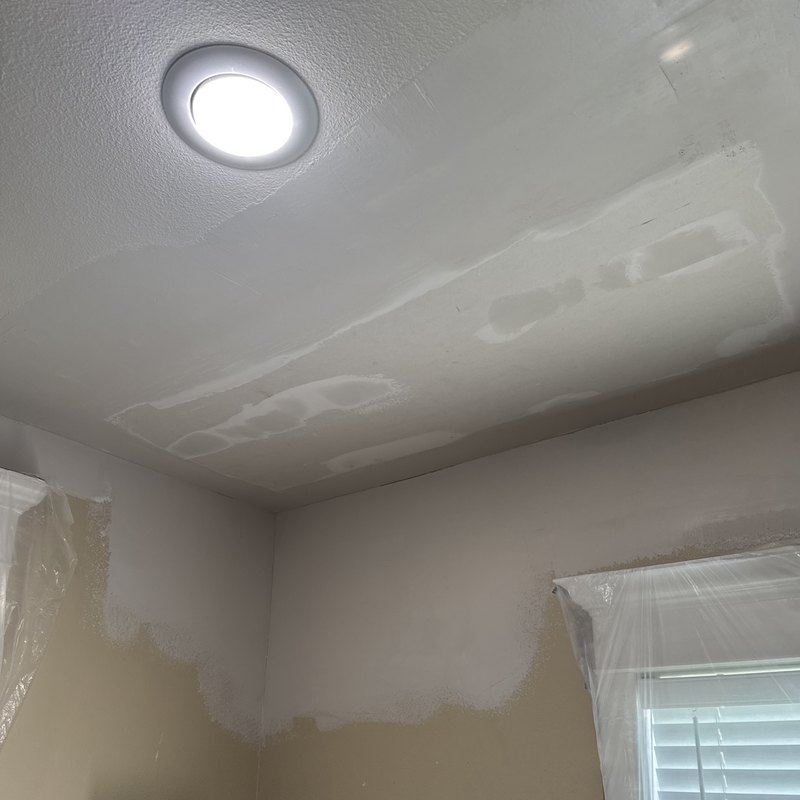 Fresh drywall patches on a ceiling before painting