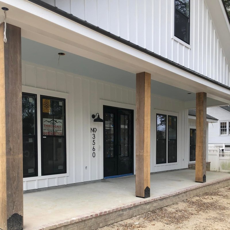 Brick-edged concrete porch on a new white home with black windows